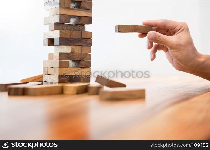 Business man placing wooden block on a tower concept of risk control planning risk and strategy