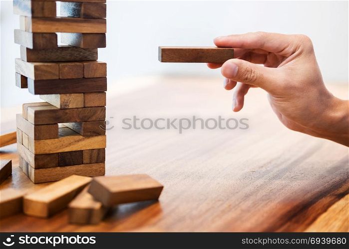 Business man placing wooden block on a tower concept of risk control planning risk and strategy