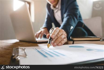 business man pointing at business document with laptop at a workplace