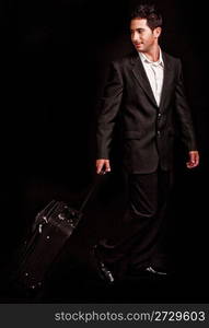 Business man pulling his luggage on black isolated background