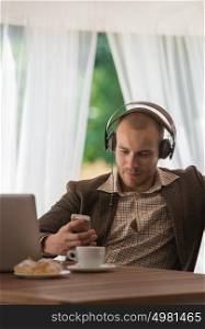 Business man resting at cafe and listening music using vintage headphones