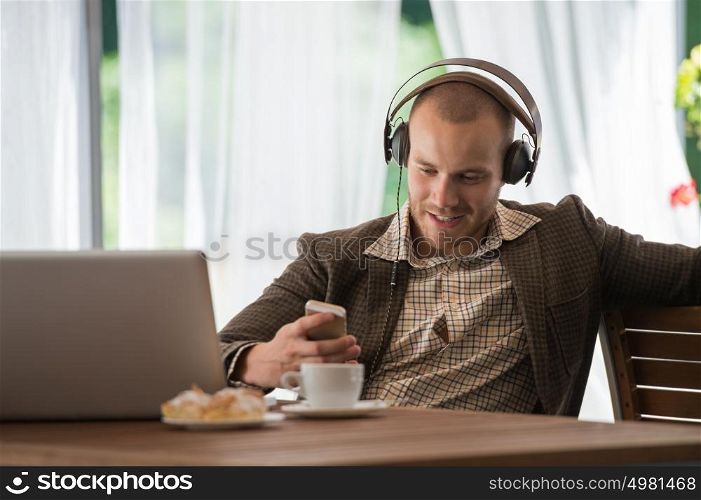 Business man resting at cafe and listening music using vintage headphones