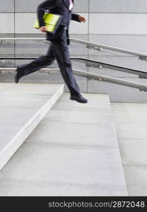 Business man running down steps outdoors side view low section