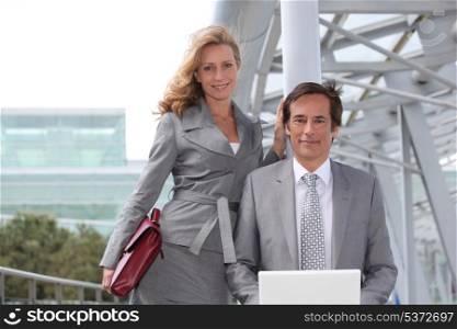 Business man sat with laptop next to female colleague