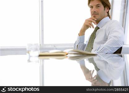 Business man sitting at conference table, portrait