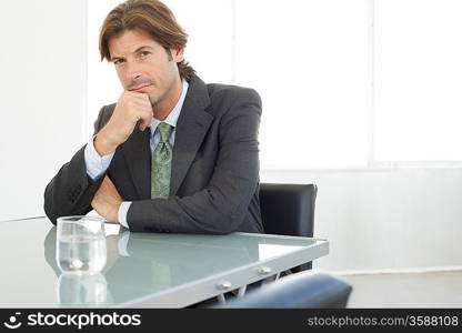Business man sitting at conference table, portrait
