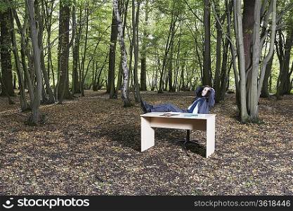 Business man sitting at desk in forest