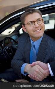 Business man sitting in car, shaking hands