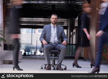 business man sitting in office chair, people group passing by: Concept of time, rush, organization