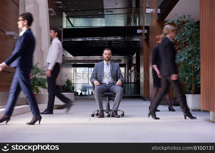 business man sitting in office chair, people group passing by: Concept of time, rush, organization