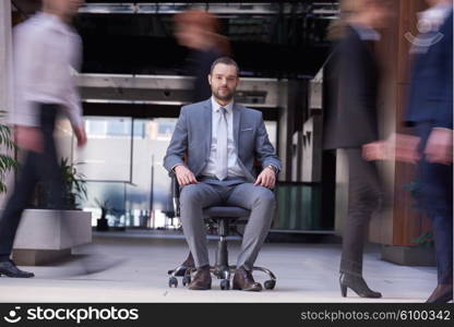 business man sitting in office chair, people group passing by: Concept of time, rush, organization