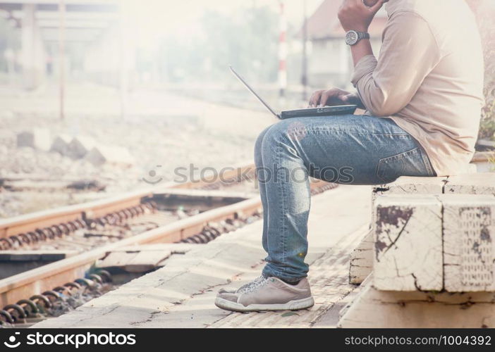 Business man sitting with a laptop in a train station.Photographed side by customizing vintage tone