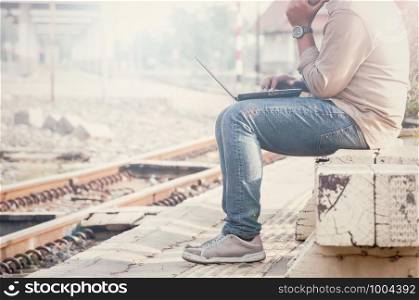 Business man sitting with a laptop in a train station.Photographed side by customizing vintage tone