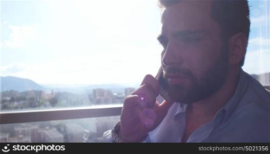 Business Man Talking On Cell Phone At Home with sun flares coming from window