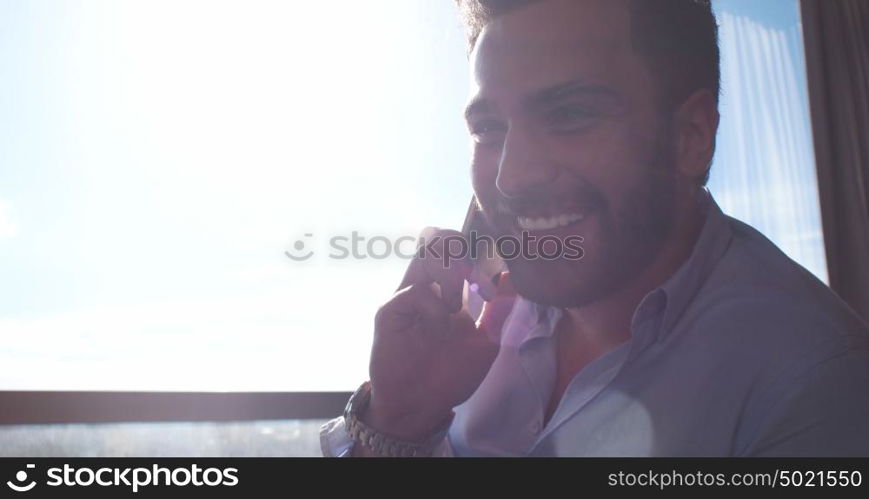 Business Man Talking On Cell Phone At Home with sun flares coming from window