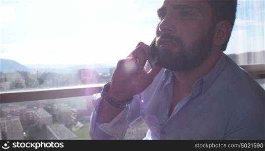 Business Man Talking On Cell Phone At Home with sun flares coming from window