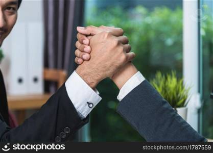 Business man two people sitting opposite at office desk and shaking hands partnership