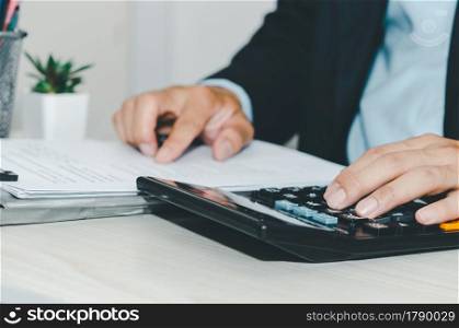Business Man using calculator at a desk. Business finance, tax, and investment concepts.