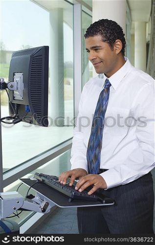 Business man using internet on computer in office hallway