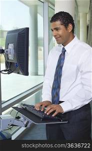 Business man using internet on computer in office hallway