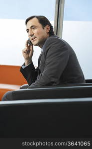 Business man using mobile phone, sitting in leather chair in office