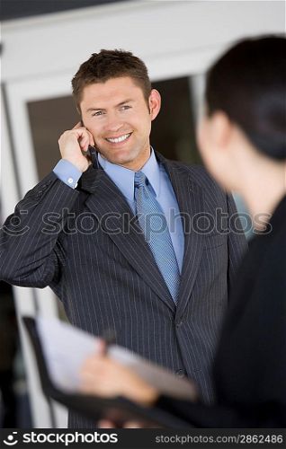 Business man using mobile phone with colleague in office