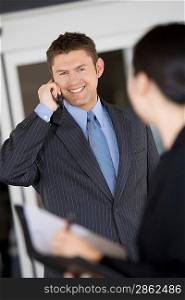 Business man using mobile phone with colleague in office
