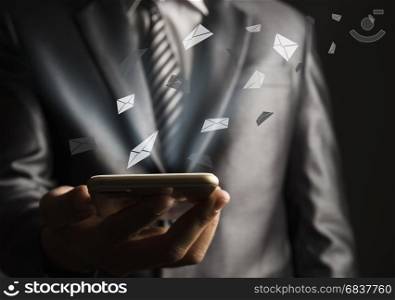 Business man using mobile phone with flying envelope
