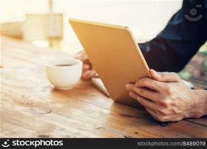 Business man using tablet on wood table in coffee shop.