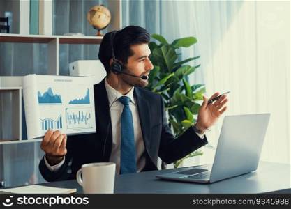 Business man wearing headphone present financial data or BI paper via laptop during online meeting. Remote work concept with virtual meeting presentation of effectiveness remote work. Fervent. Businessman with headphone present BI paper during online meeting. Fervent