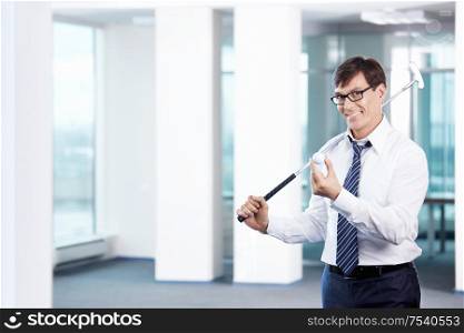 Business man with a golf club in office