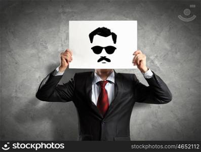 Business man with drawing. Image of businessman holding drawing against face. Conceptual photo