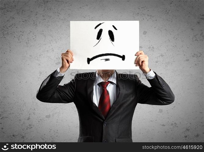 Business man with drawing. Image of businessman holding drawing of upset face. Conceptual photo