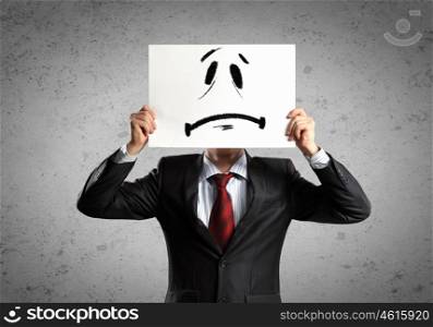 Business man with drawing. Image of businessman holding drawing of upset face. Conceptual photo