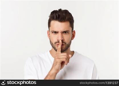 Business man with finger on lips asking for silence over white background.. Business man with finger on lips asking for silence over white background