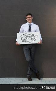 Business man with new car sign. Dealer or buyer showing car sign. Credit concept