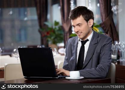 Business man with the laptop sits at a table in cafe