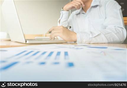 Business man working at office with laptop and documents on his desk, Financial graph data.