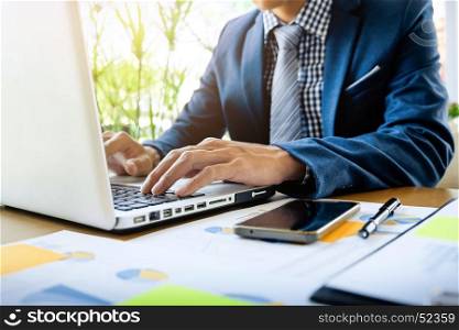 Business man working at office with laptop, tablet and graph data documents on his desk