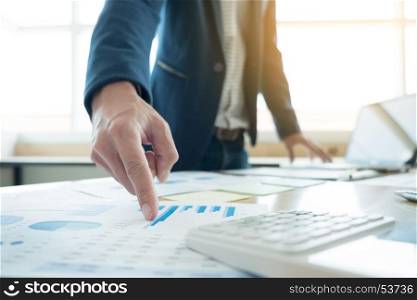 Business man working at office with laptop, tablet and graph data documents on his desk