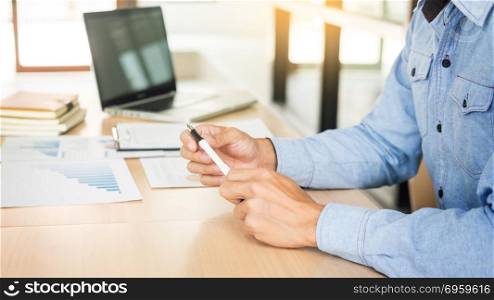 Business man working at office with laptop, tablet and graph data documents on his desk.. Business man working at office with laptop, tablet and graph dat