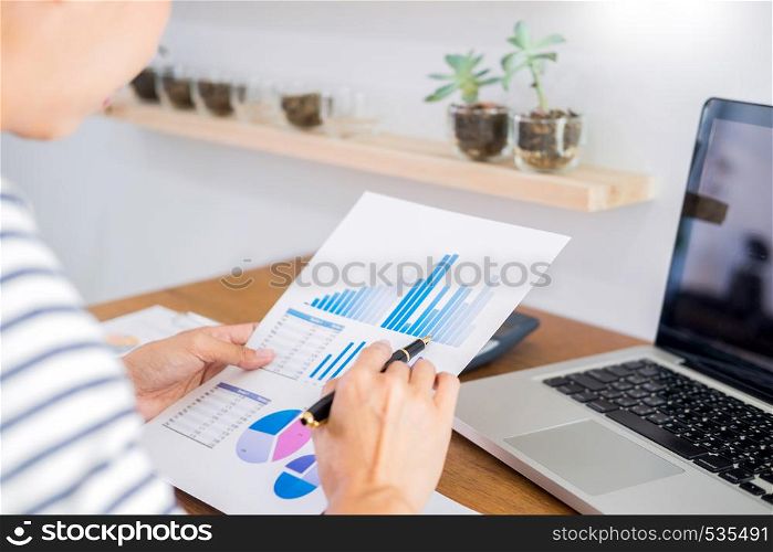 business man working on a laptop tablet and graph data documents on his desk in home office