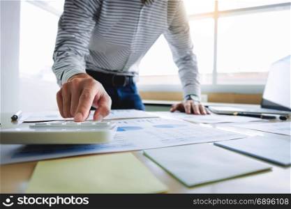 business man working on business documents, calculator and laptop at a workplace