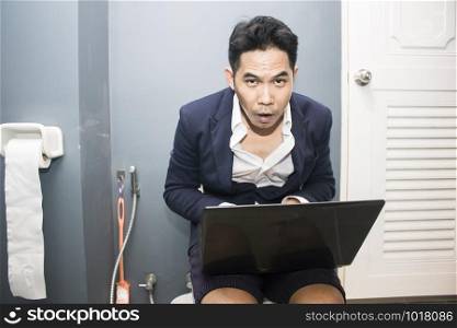 Business man working on his computer while on the toilet