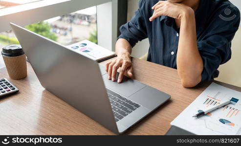 Business man working with graph data in laptop and documents on his desk at office