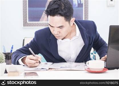 Business man writing on notepad in office