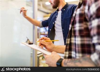 business, manufacture and people concept - men writing to clipboard and whiteboard at office. men writing to clipboard and whiteboard at office. men writing to clipboard and whiteboard at office