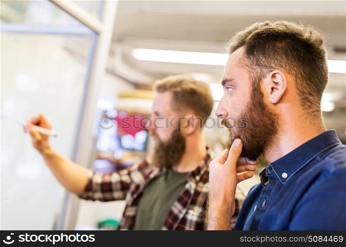 business, manufacture and people concept - men writing to whiteboard at office. men writing to whiteboard at office. men writing to whiteboard at office