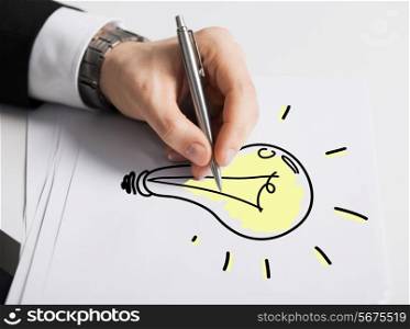 business, marketing, planning and people concept - close up of male hand with pen drawing bulb on white paper