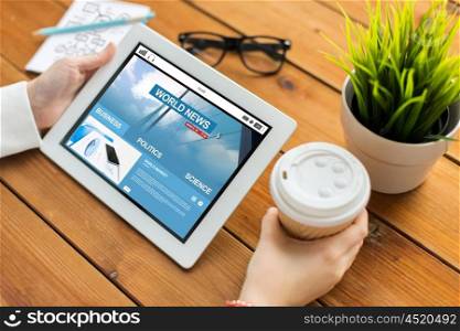 business, mass media, technology, people and advertisement concept - close up of woman with world news web page on tablet pc computer screen and coffee cup on wooden table